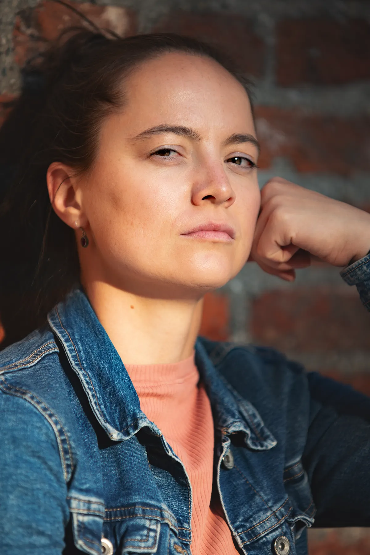 Theresa Kempf, Schauspielerin bei ZeitweiseZeitreisende, nachdenkend vor Backsteinwand.